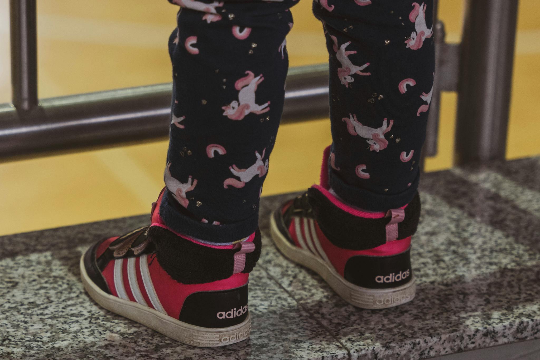 Adorable child's feet in unicorn leggings and sneakers, showcasing playful fashion for kids.