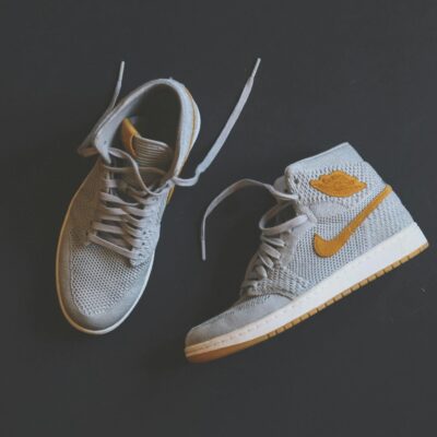 Close-up of fashionable gray and orange high-top sneakers displayed against a minimal background.