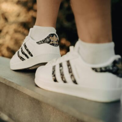 Close-up of white sneakers with black accents on a metal ledge, outdoors.