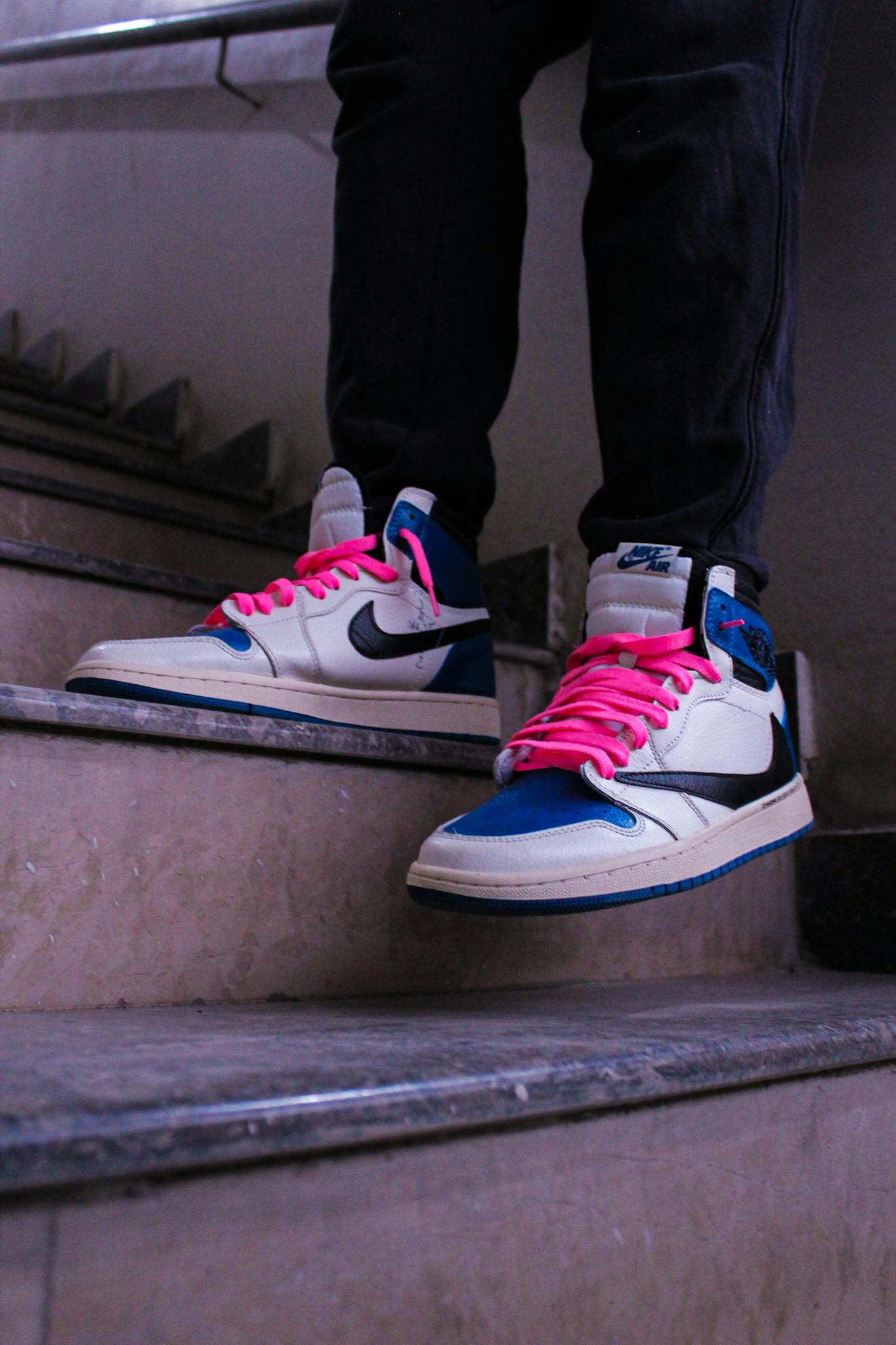 Fashion-forward sneakers with bold pink laces spotted on stairs, perfect for urban style inspiration.